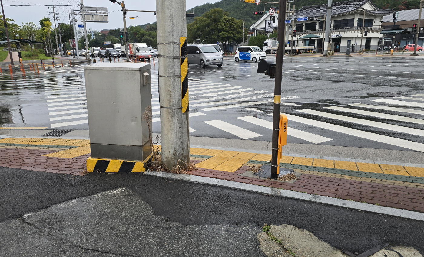 횡단보도 앞 점자블록이 전봇대·전기함에 막힌 데다 방향선마저 엉뚱한 곳을 가리킨다. 시각장애인에게는 안내가 아니라 곧바로 위험으로 이어지는 길이다 (용강동 올리브영앞). 오선아 기자.