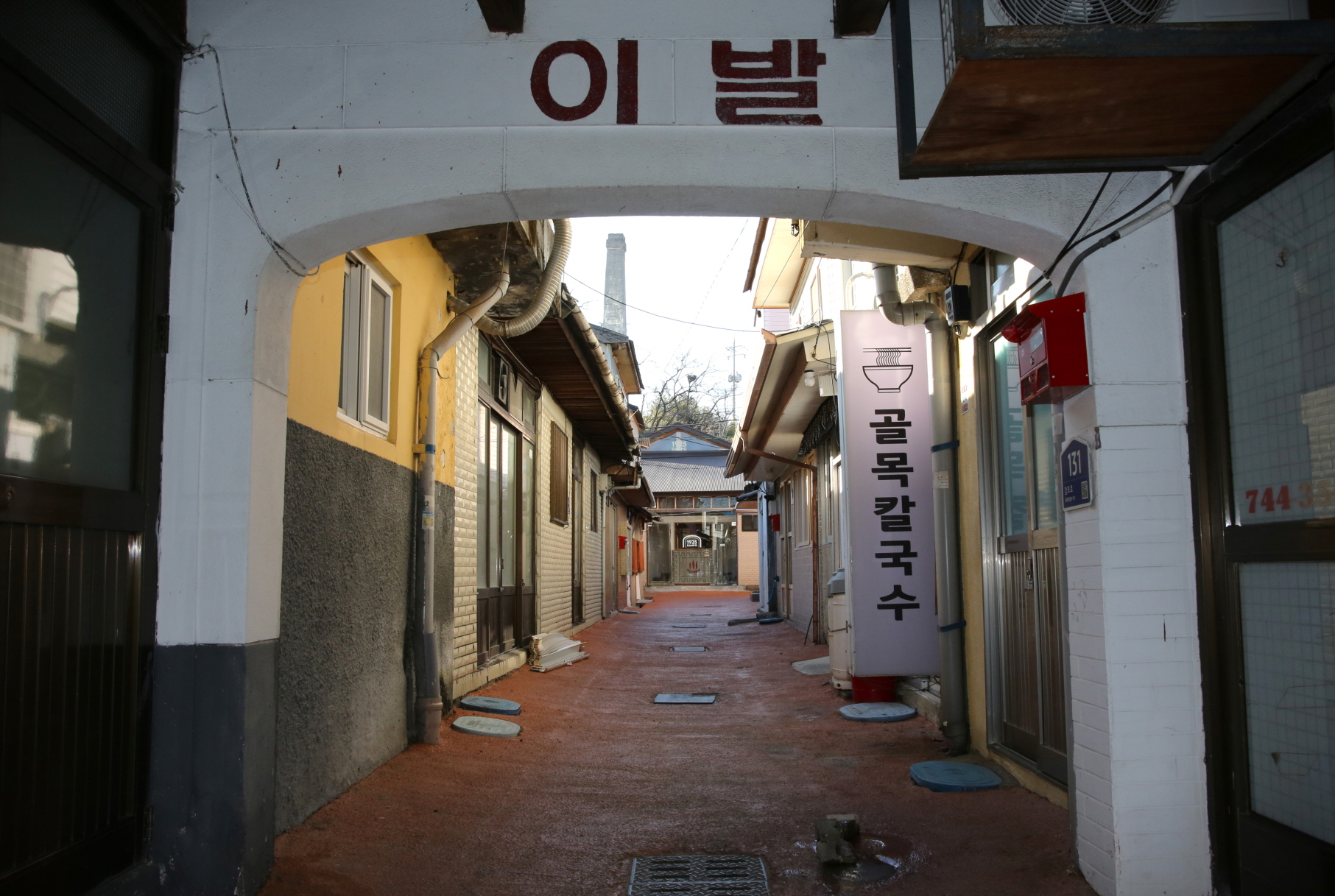 해국길에서 감포읍 중심도로로 이어지는 아케이드 길. 2층짜리 건물이 쭉 늘어서 있는 건물의 아랫부분이다. 맞은편 건물이 목욕탕 건물을 새단장해 들어선 복합문화공간 ‘1925 감포’다. 멀리 우뚝 솟은 굴뚝이 보인다. <사진=김운 역사여행가>